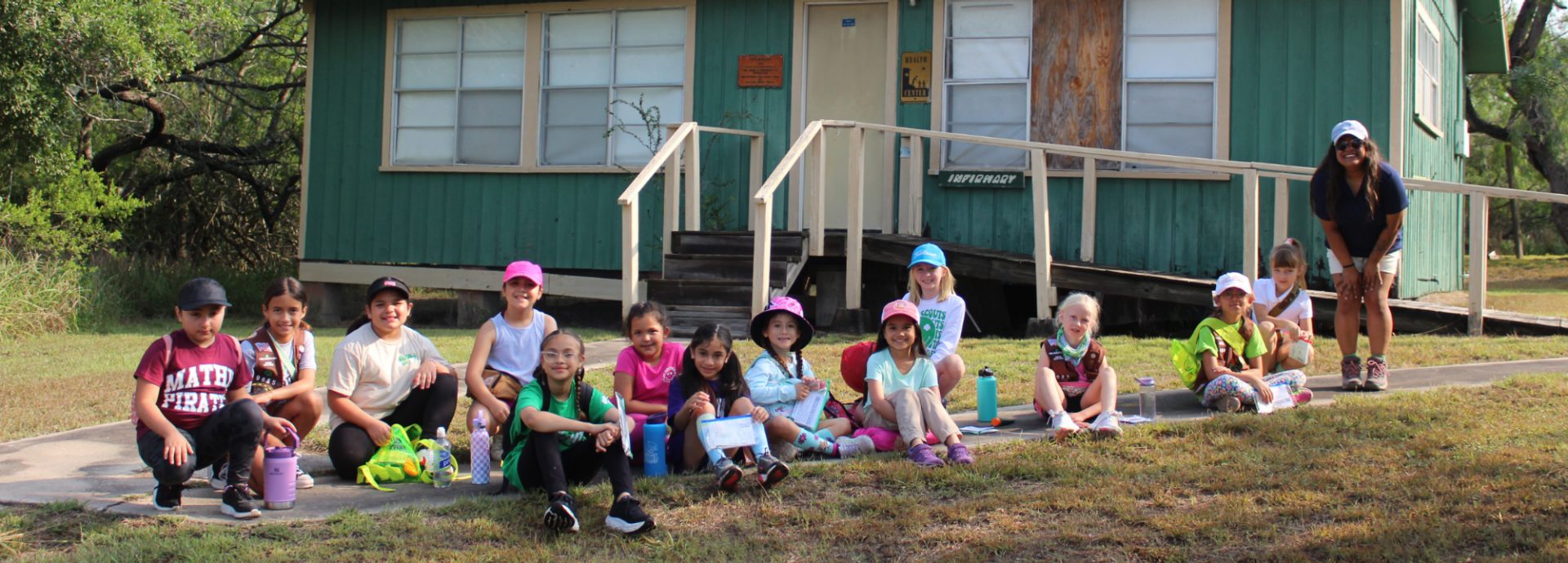  Two daisy kindergarten Girl Scouts holding lantern in tent camping wearing trefoil shirt. 