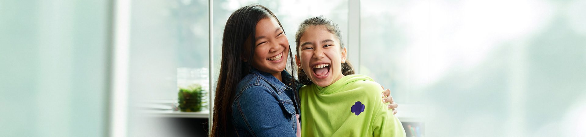  two high school girls hugging while staring at the camera with content facial expressions 