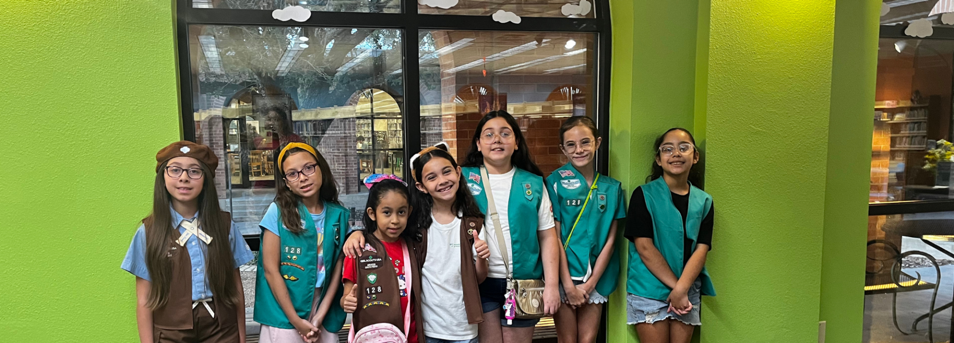  group of girl scouts walking outside smiling at camera 