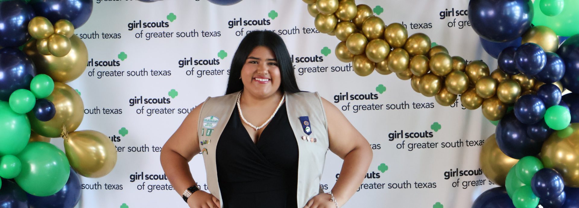  portrait of ambassador girl scout wearing vest and smiling at camera in front of a brick building 